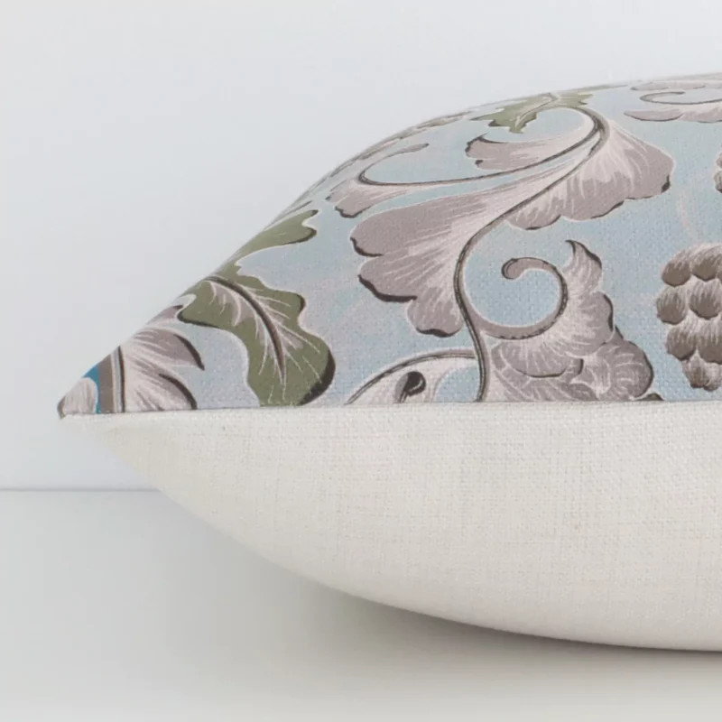 Lateral angle image of a linen square cushion. The colourful print and patterned design are highlighted along its seams.