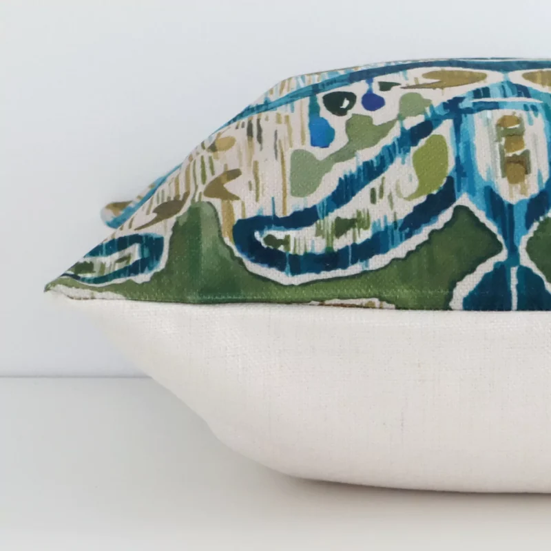A linen colourful cushion cover shown laying on its side. The patterned design and its square size are shown side on.