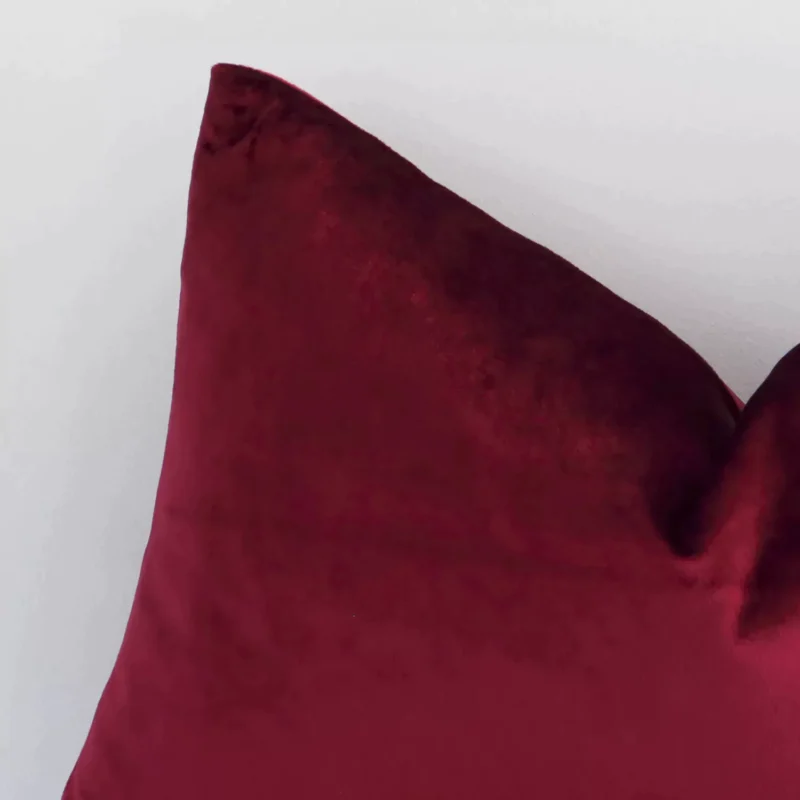 Macro image of a velvet rectangle cushion cover. The shot shows the burgundy hue and solid-coloured style more thoroughly.