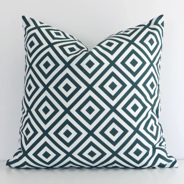 Green square cushion positioned in front of a white wall. It has geometric dimensions and is made from an outdoor material.