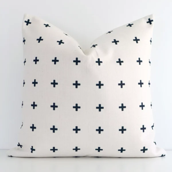 A white wall that has a black patterned cushion cover positioned in front of it. It has an exquisite linen material and a lovely square shape.