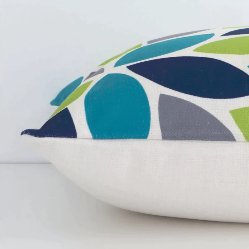 Square patterned cushion in colourful print laying flat. The viewpoint highlights the seams of the linen fabric.