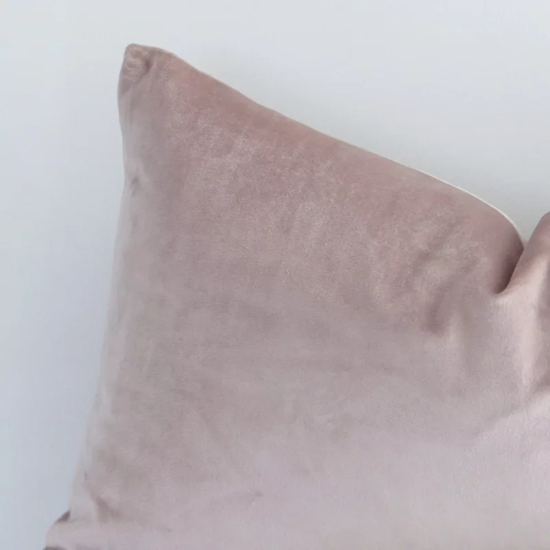 A close up image of this solid-coloured rectangle cushion. The image shows details of its velvet fabric and dusty pink colour.