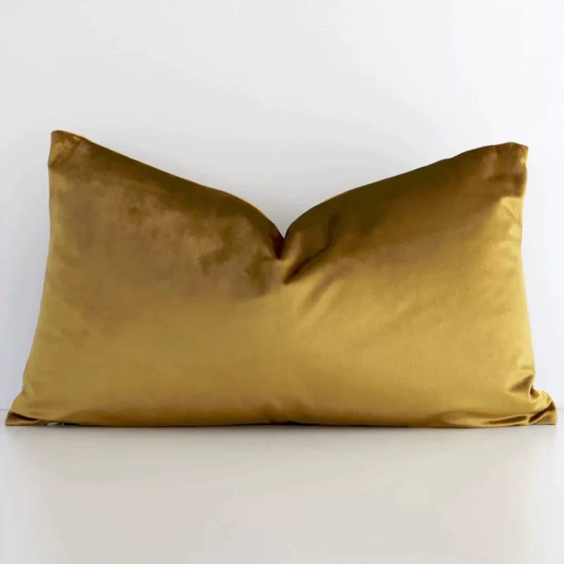 gold-mustard-velvet-linen-rectangular-cushion-cover---rectangle---sc509-30 A rectangle solid-coloured cushion in a delightful gold mustard tone rests against a white wall. The velvet material appears to be of exceptional quality.