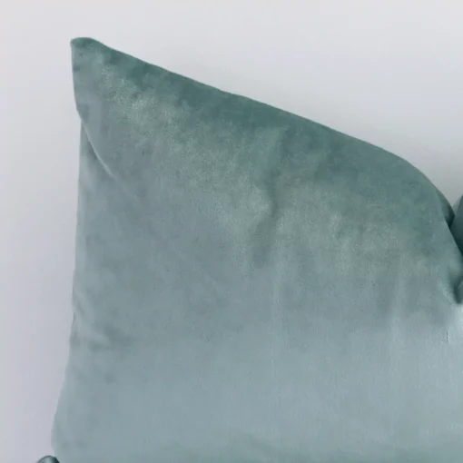 The corner of this mint green velvet cushion is shown close up. The finer detail of its rectangle design and solid colour finish can be seen.