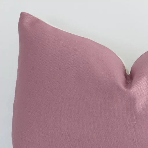 A linen rectangle cushion’s corner has been enlarged in this shot. The detail of the solid-colour blush colour is visible.