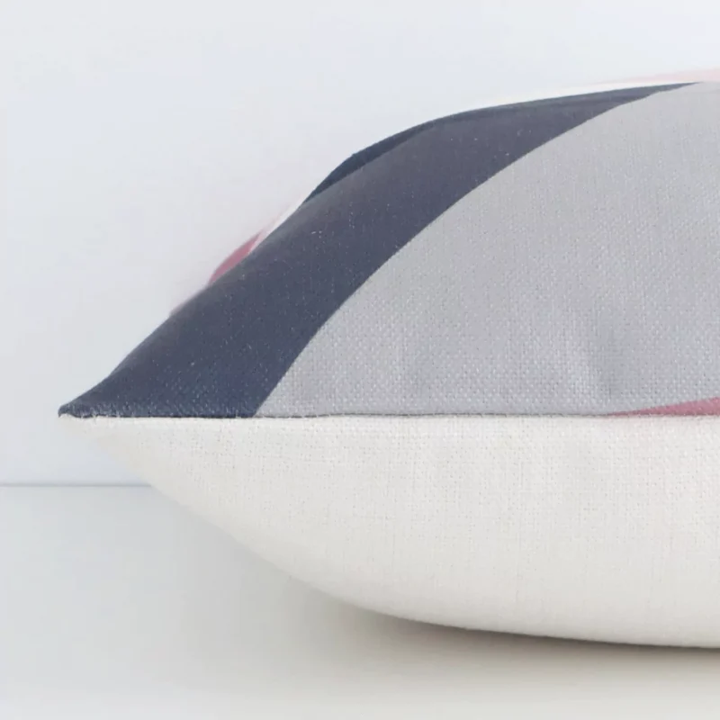 Square colourful cushion laid flat. This view shows the geometric style and linen fabric from side on.