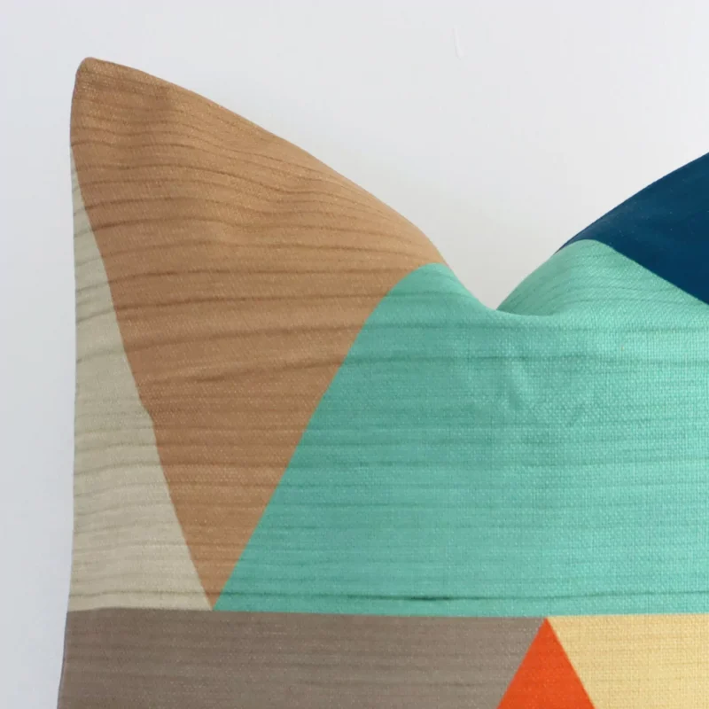 Cropped shot of top left corner of this geometric colourful cushion cover. This viewpoint shows the linen fabric and square shape with more precision.