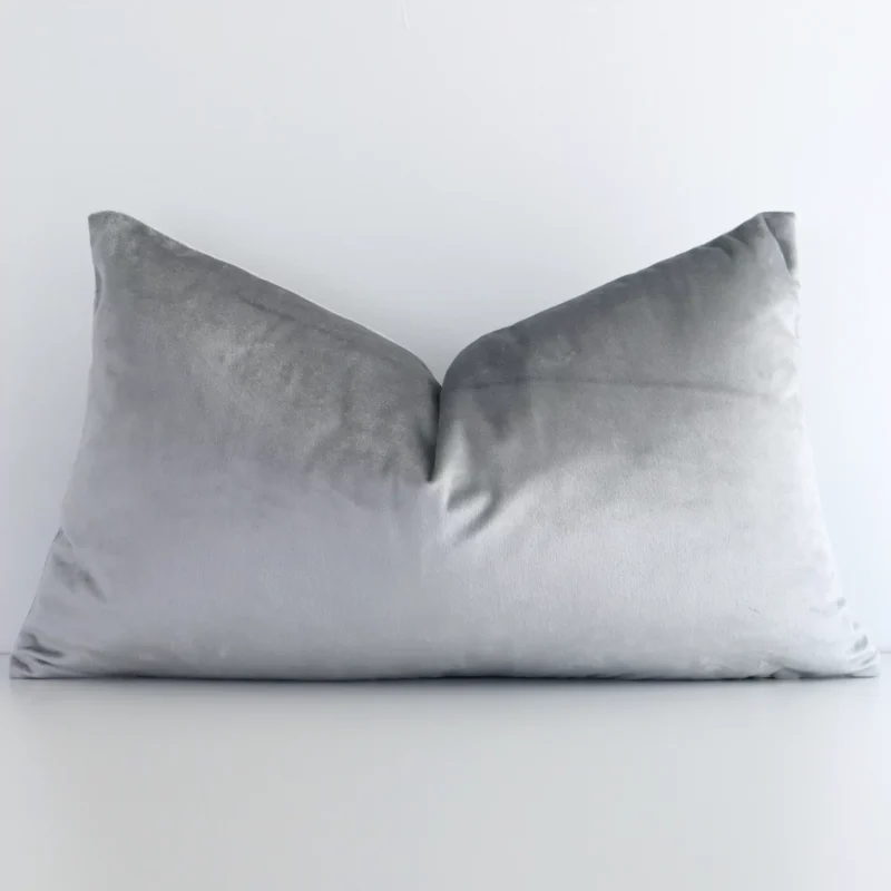 silver-velvet-linen-rectangular-cushion-cover---rectangle---sc502-30 Velvet rectangle cushion with a solid-coloured design in an upright position against a white brick wall. It is silver in colour.
