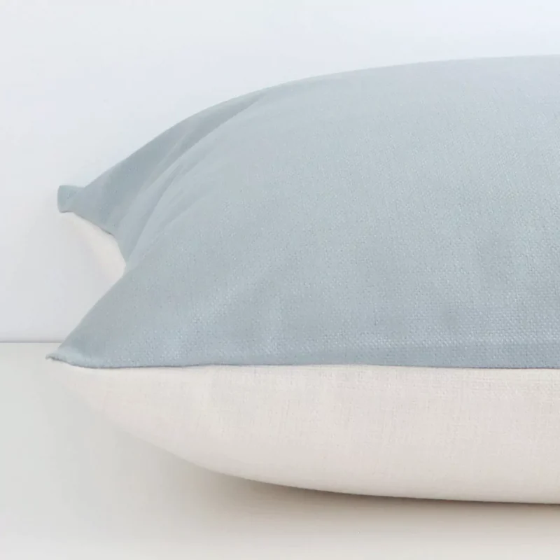 The edge of this linen large cushion in soft teal is shown. The shot shows the solid colour design and the front and rear panels.