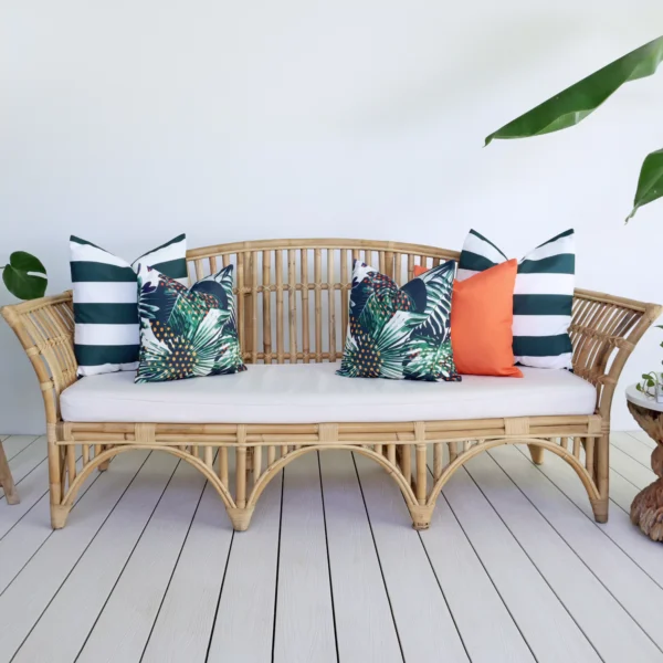 A rattan seat in bright living area displays a set of 5 Byron floral outdoor cushions.