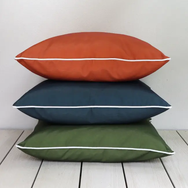 A tower of large outdoor cushions balanced on external flooring.