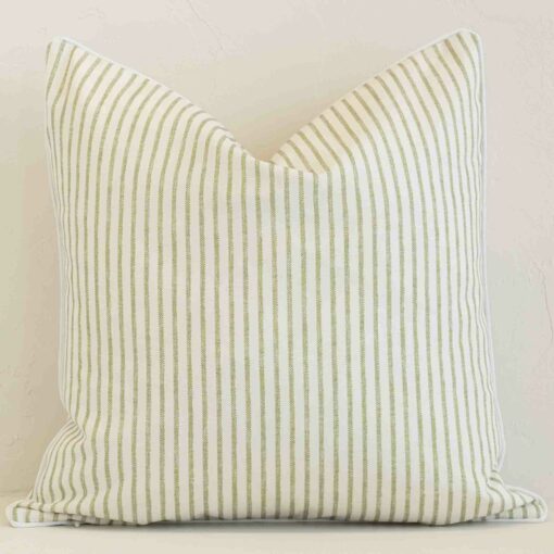 An attractive striped outdoor cushion in front of a white brick wall. It has a square shape and is sage in colour.
