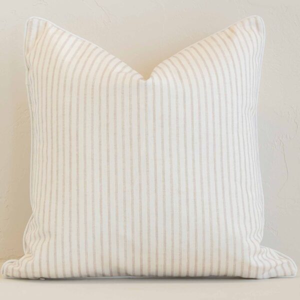 White wall with a stripe sand cushion laying against it. It has a distinctive outdoor fabric and has a square shape.