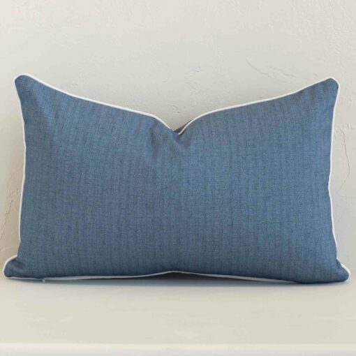 Blue outdoor cushion cover features prominently against a white wall. It is a rectangle design and has a solid-coloured decorative finish.