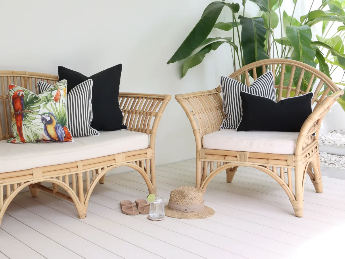 A collection of black and white outdoor cushions, along with a vibrant parrot print, adorn a patio setting.