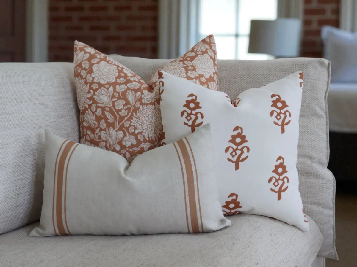 A cushion combo arranged on a sofa in a modern home featuring terracotta designs.