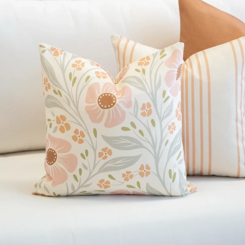 A set of 3 desert bloom outdoor couch cushions are tucked in the corner of a white sofa.