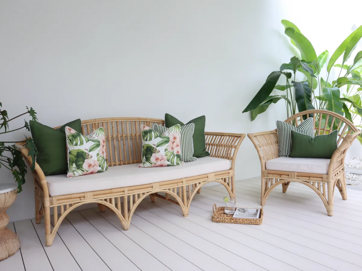 Green tropical outdoor cushions are arranged well on an outdoor sofa and a matching outdoor armchair.