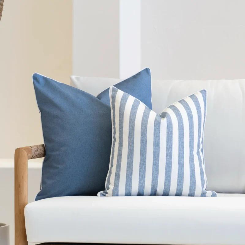 2 outdoor pacific blue outdoor cushions are arranged on a white sofa.