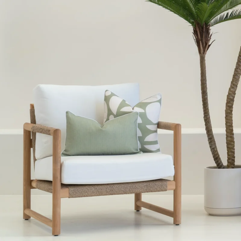 White armchair with 2 outdoor cushions carefully arranged on it.