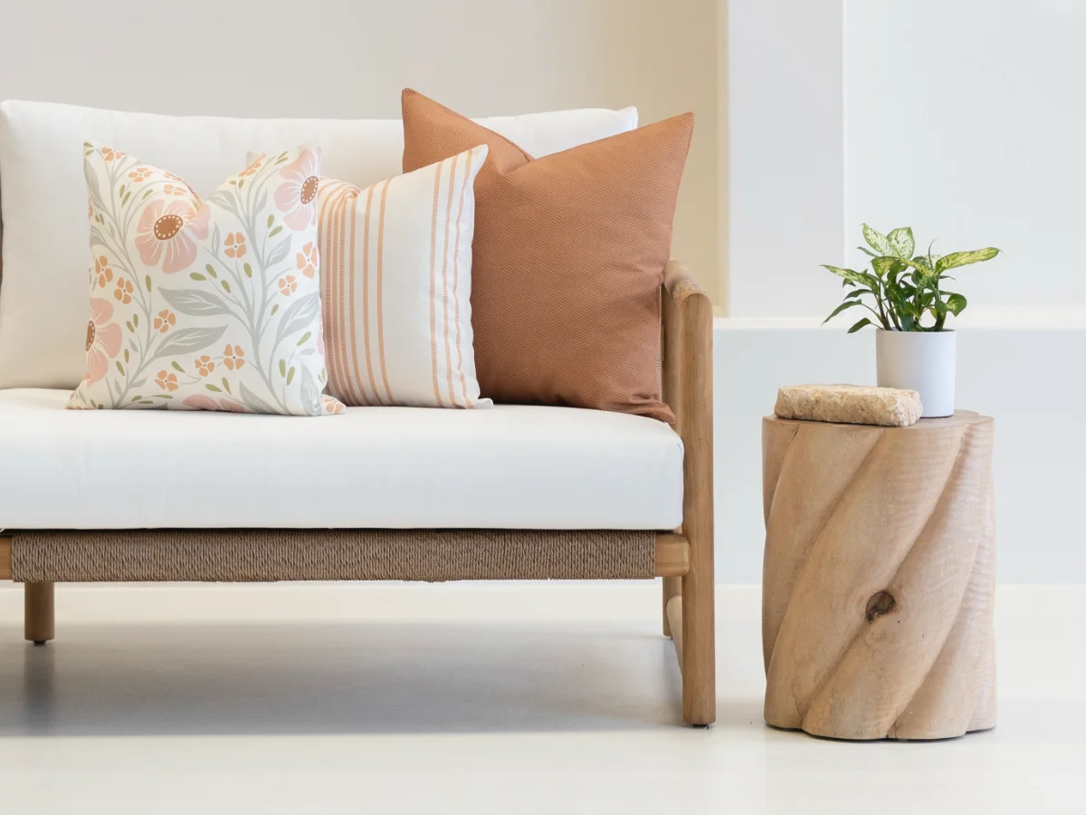 An arrangement of outdoor cushions that follows the solid + stripe + floral formula sitting on an outdoor sofa.