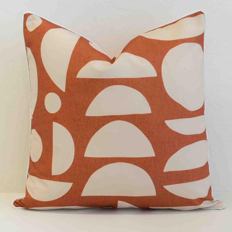 Pacific geometric rust cushion with cream abstract pattern on plain background.