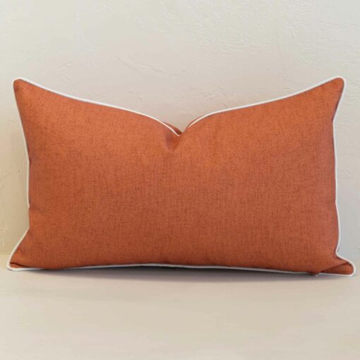 Pacific rust rectangular cushion with textured fabric and white piping edges.