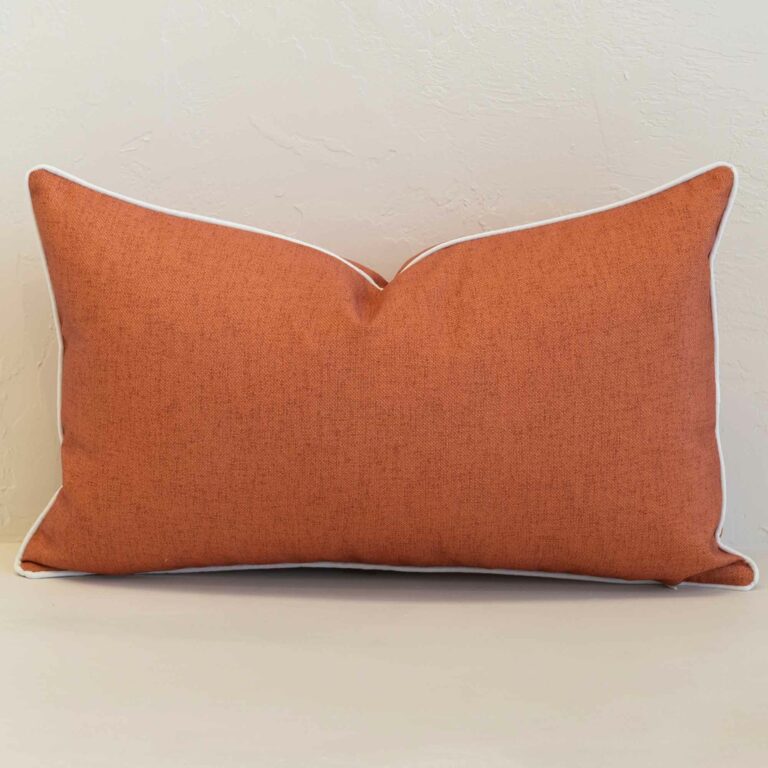 Pacific rust rectangular cushion with textured fabric and white piping edges.