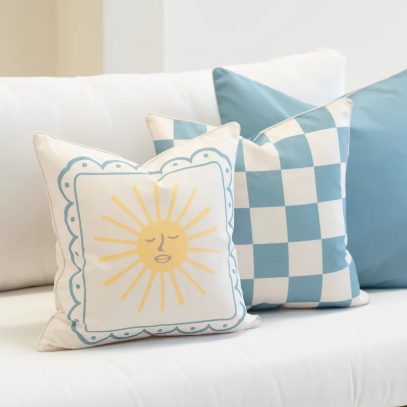 Close-up of Tropica aqua cushions with sun design and blue check pattern.