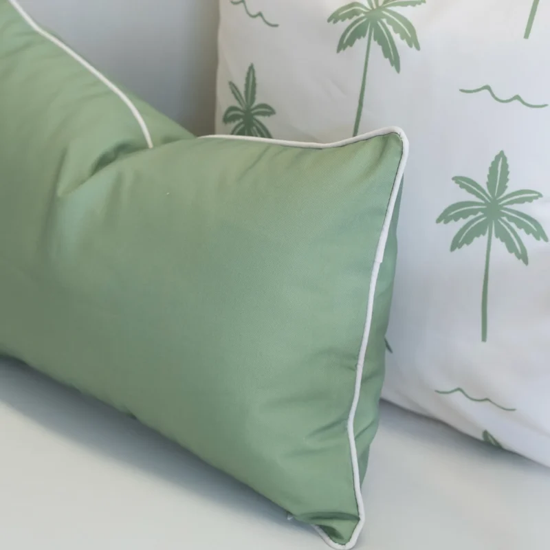 Close-up of Tropica green cushion with piping beside palm print cushion.