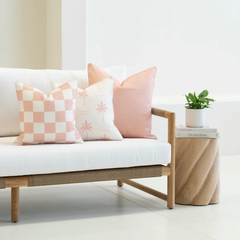 Tropica pink cushions with check and palm patterns on outdoor sofa.
