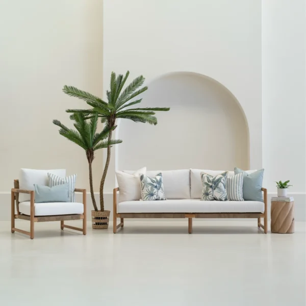 Wildgrove frond outdoor cushions styled on sofa and chair with palm nearby.