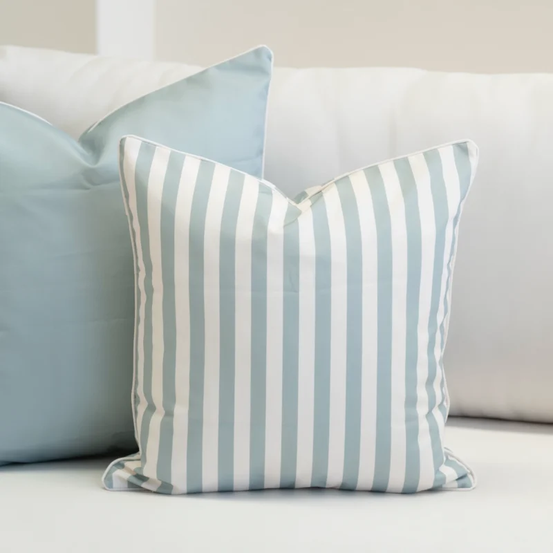 Striped blue and white Wildgrove Palm cushion beside solid blue cushion.