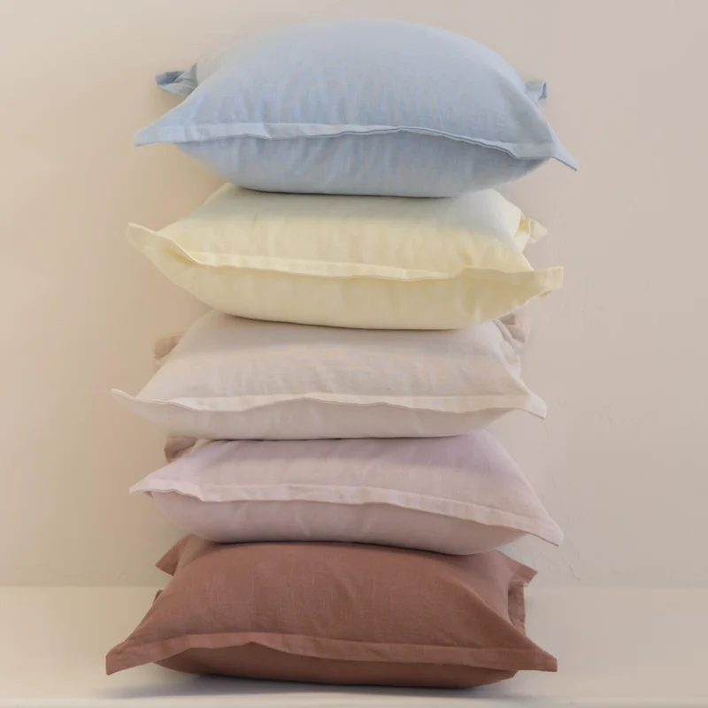 Pastel linen cushions stacked vertically with soft blue, yellow and neutral shades.