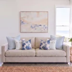 Six-piece cushion set with matching sky blue linen, white button, and coral print cushions, on a sofa.