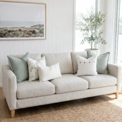 Five-piece cushion set with two sage blocks, a botanical print, and button and boucle lumbar accents, on a sofa.